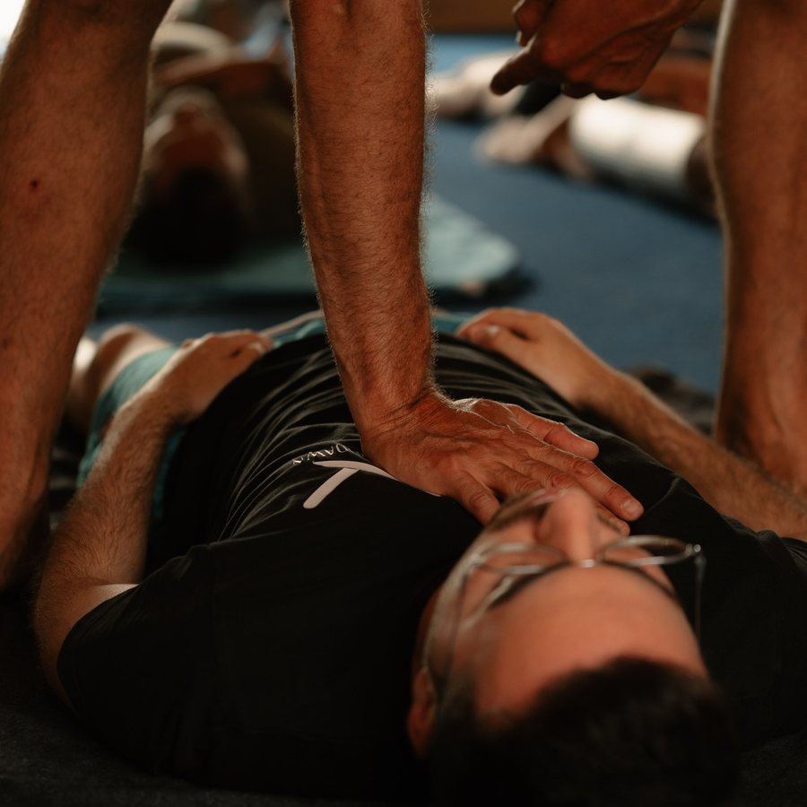 Mano del instructor sobre el pecho de un alumno tumbado, trabajo de respiración